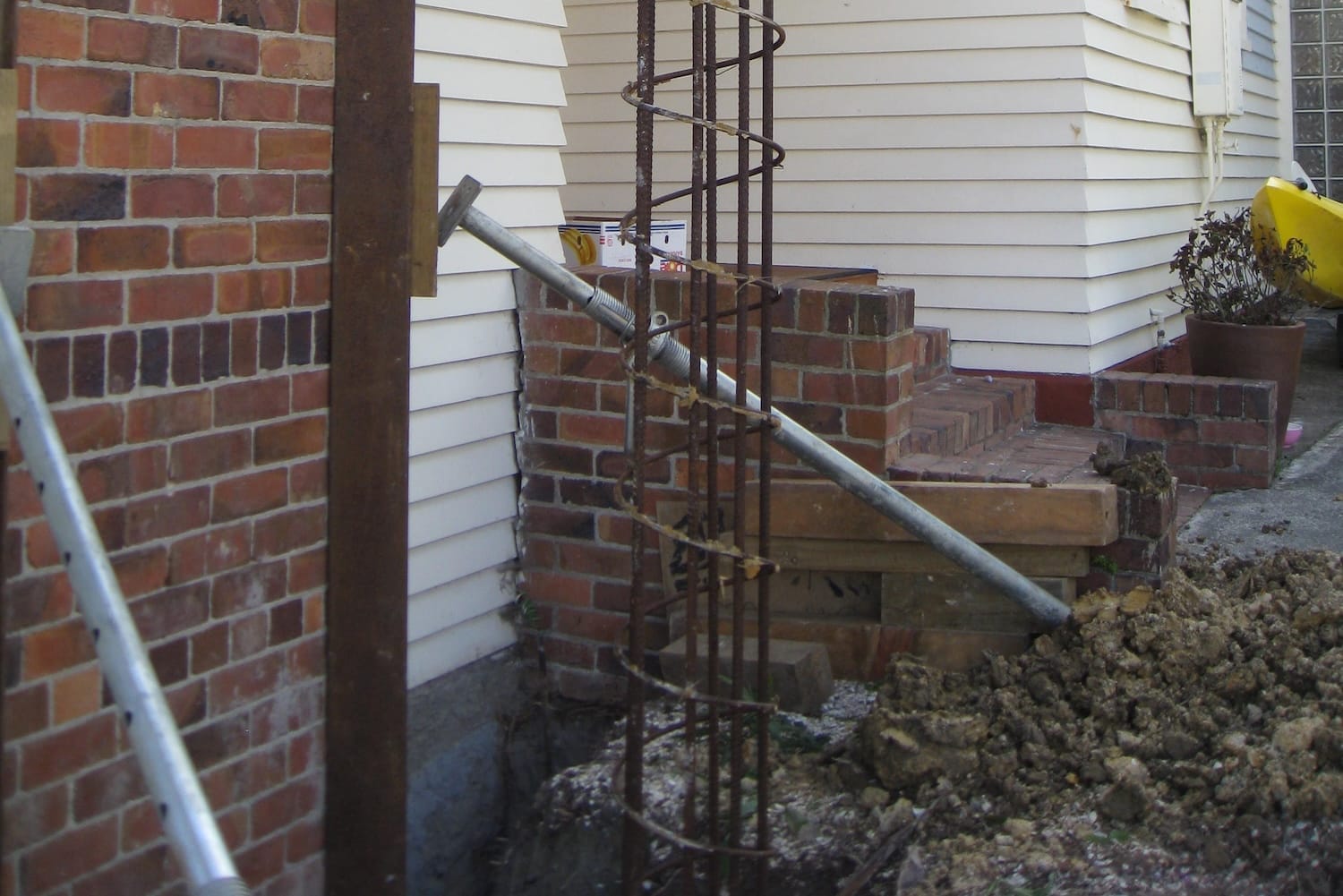 foundation-reinforcement-rebar-column-installation Steel rebar column installed beside a house for foundation reinforcement during lifting work