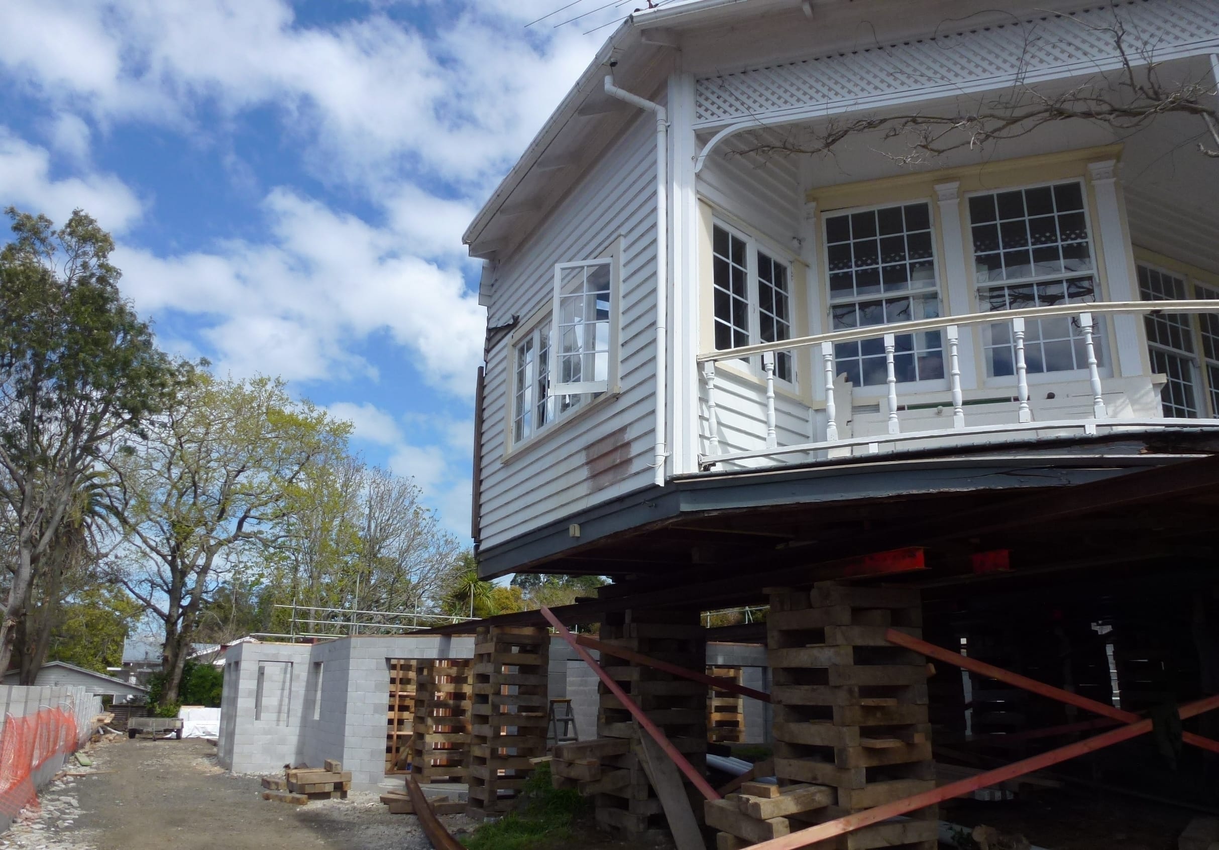 Elevated house with veranda supported on timber cribbing during foundation reconstruction