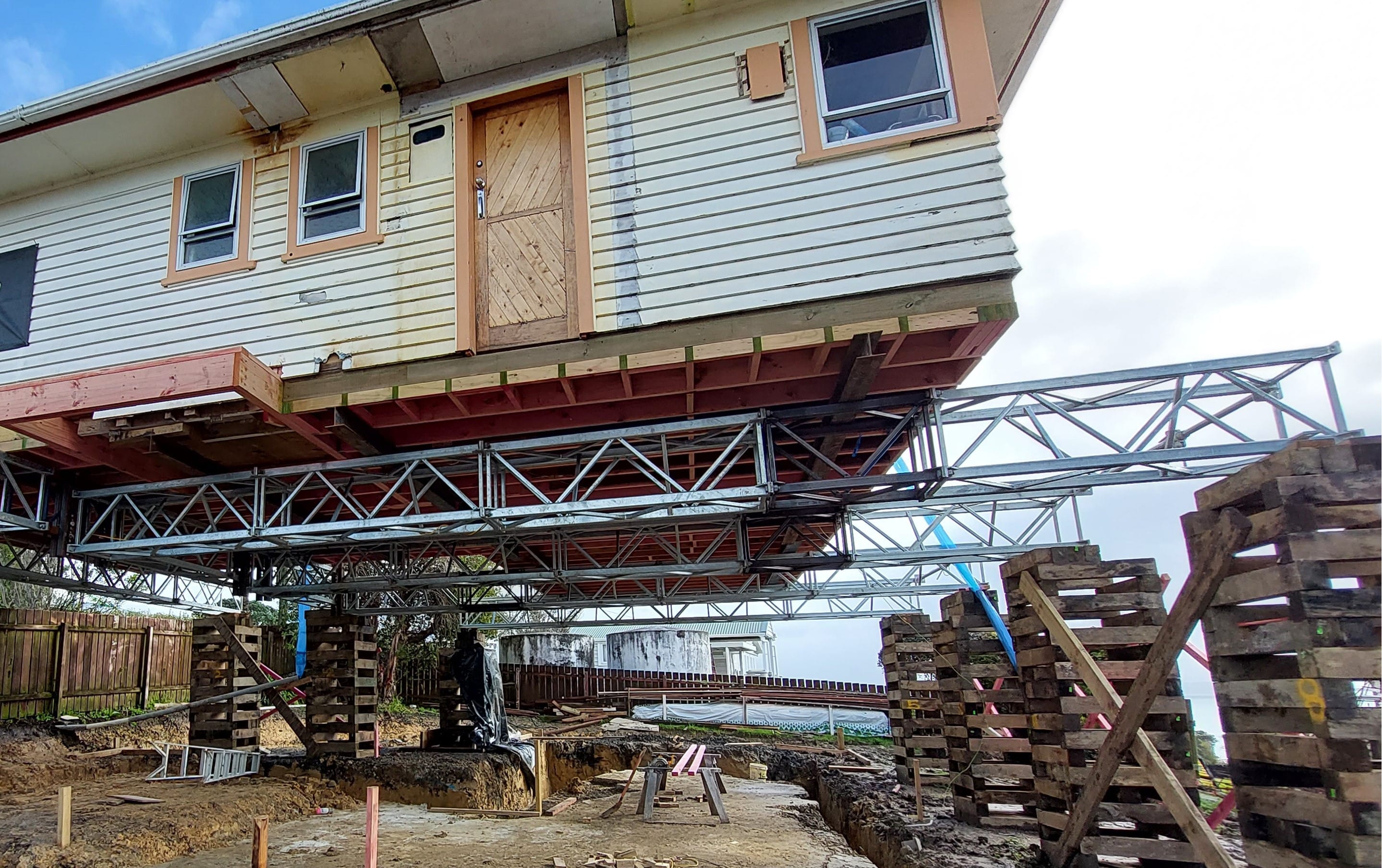 House lifting with steel beams and timber crib supports during foundation preparation work