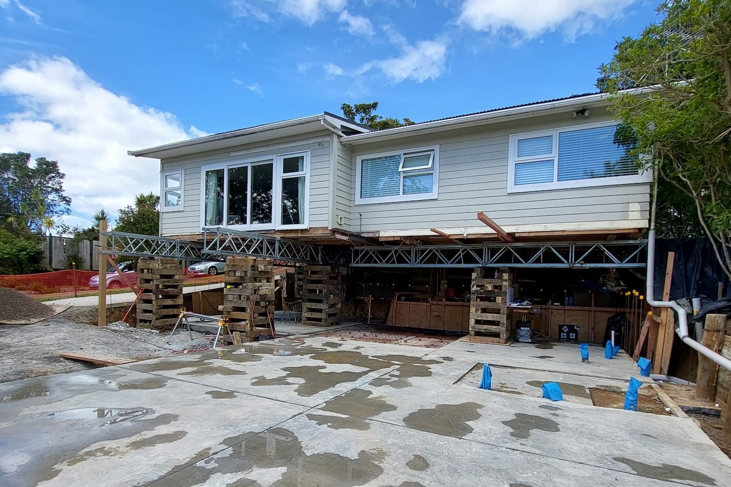 house-lifting-steel-beams-timber-cribbing-concrete-slab House lifted on steel beams and timber cribbing above a new concrete slab foundation