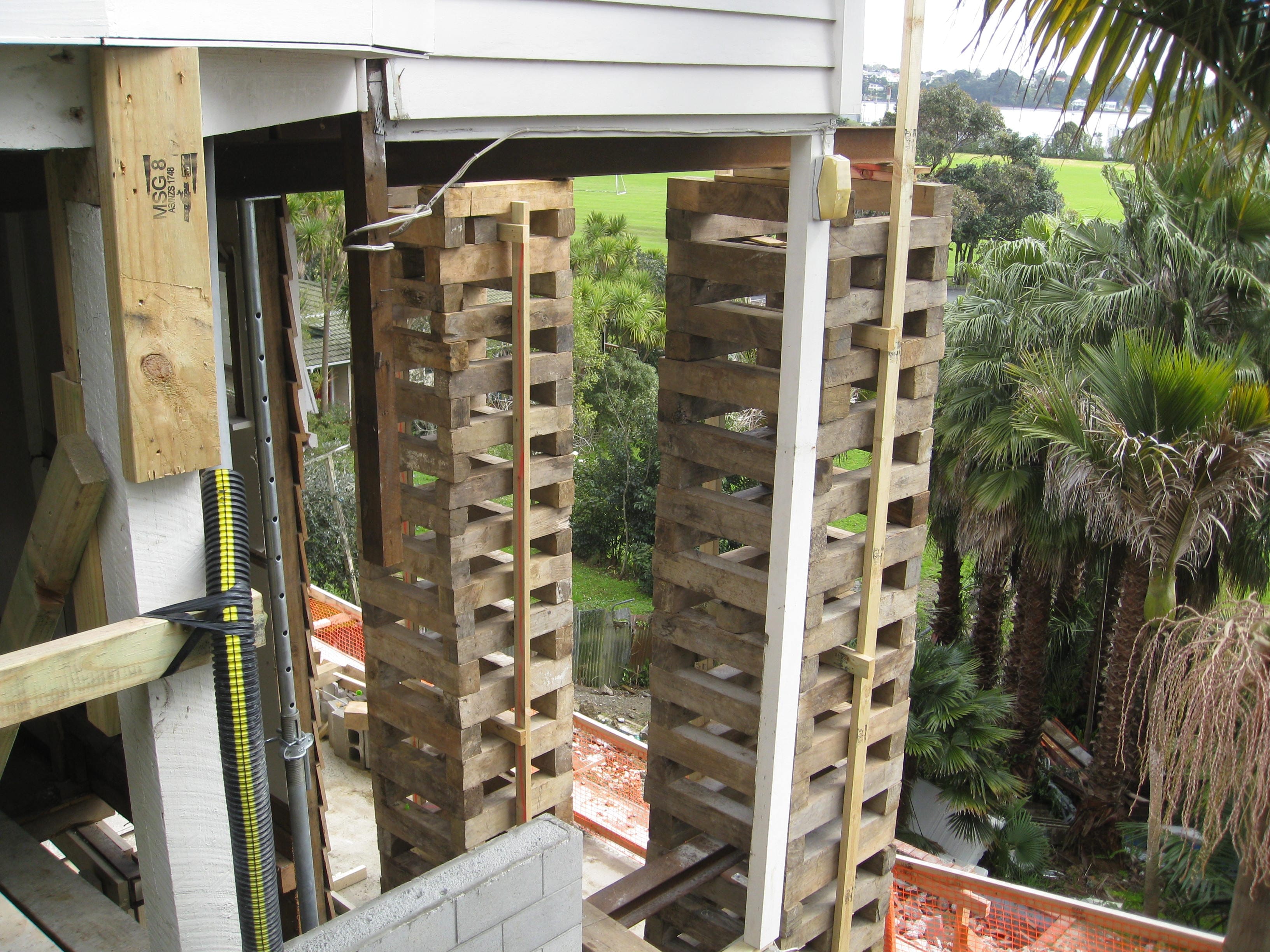 Elevated house supported by stacked timber cribbing during re-piling and foundation repair work