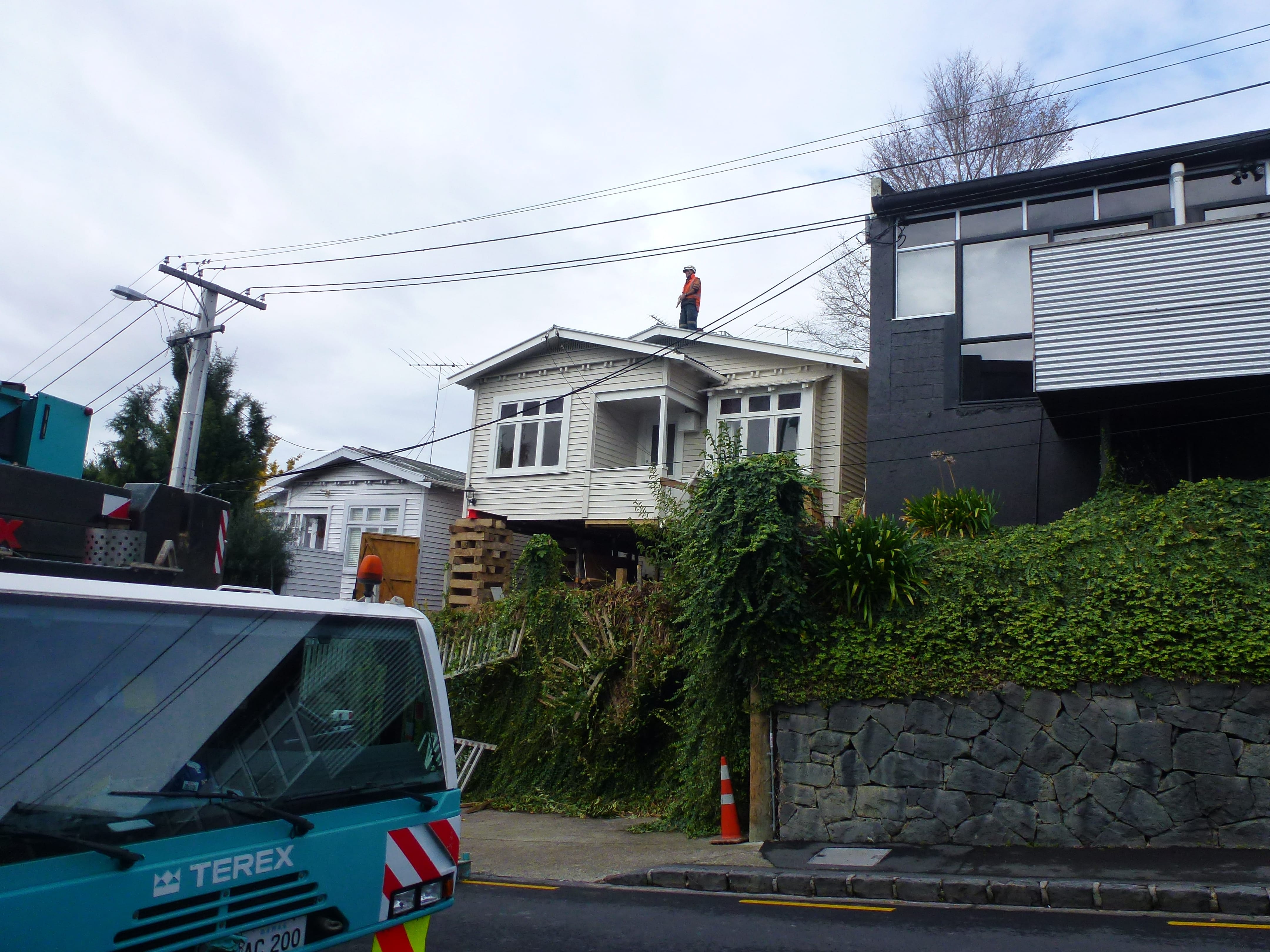 House lifting project on a sloped urban site with crane access and elevated structure